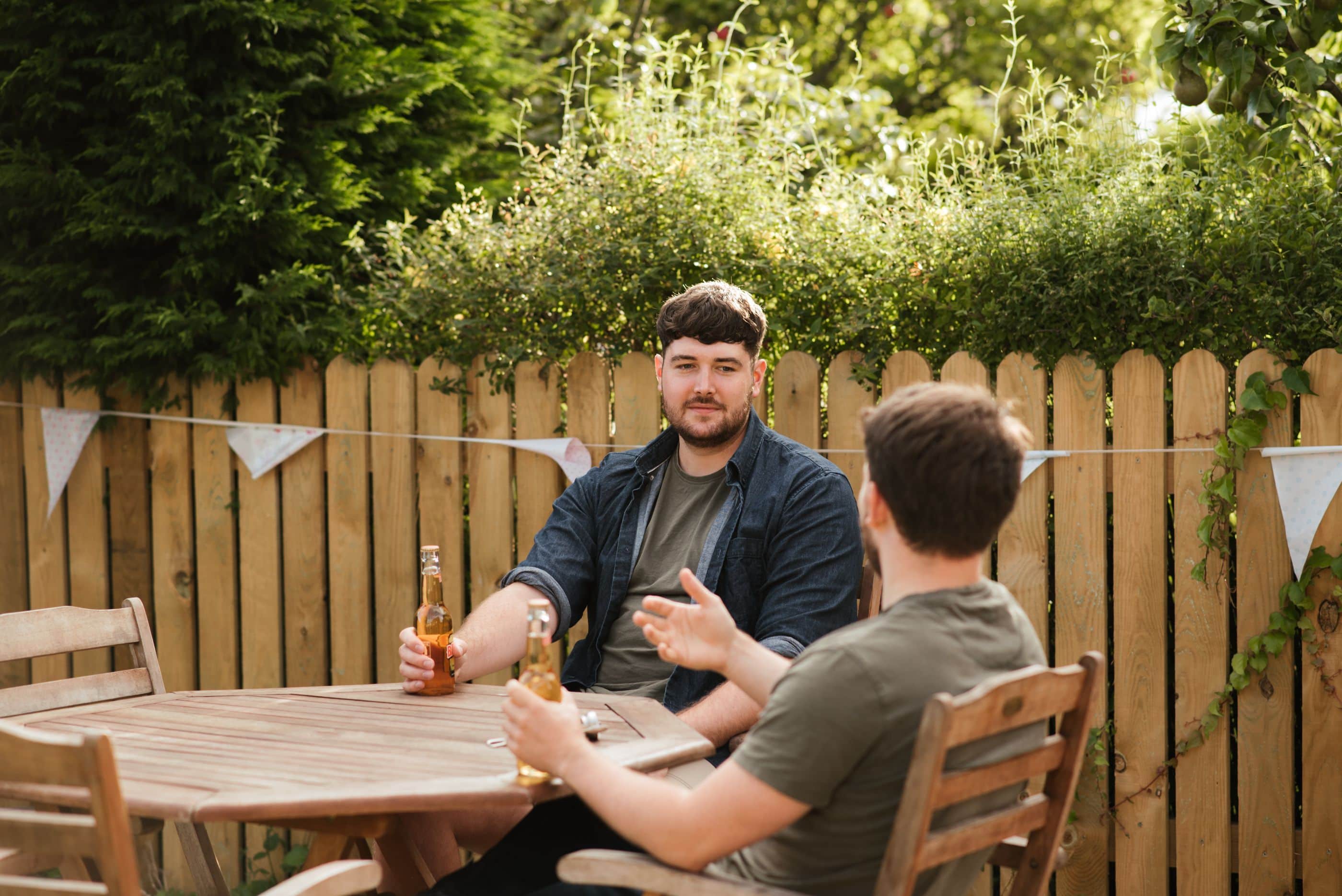 Twee buren in gesprek aan tafel in de tuin
